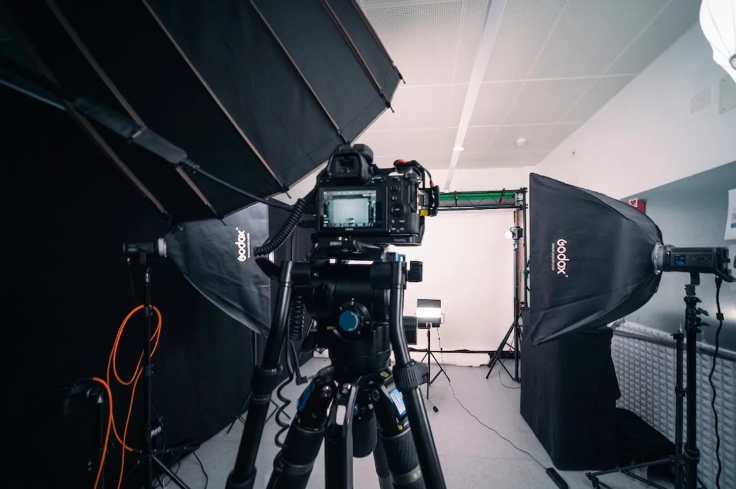 Le studio de Marly éclairé pour une prise de vue : caméra sur pied fluide entre deux softbox, cyclorama blanc au fond.