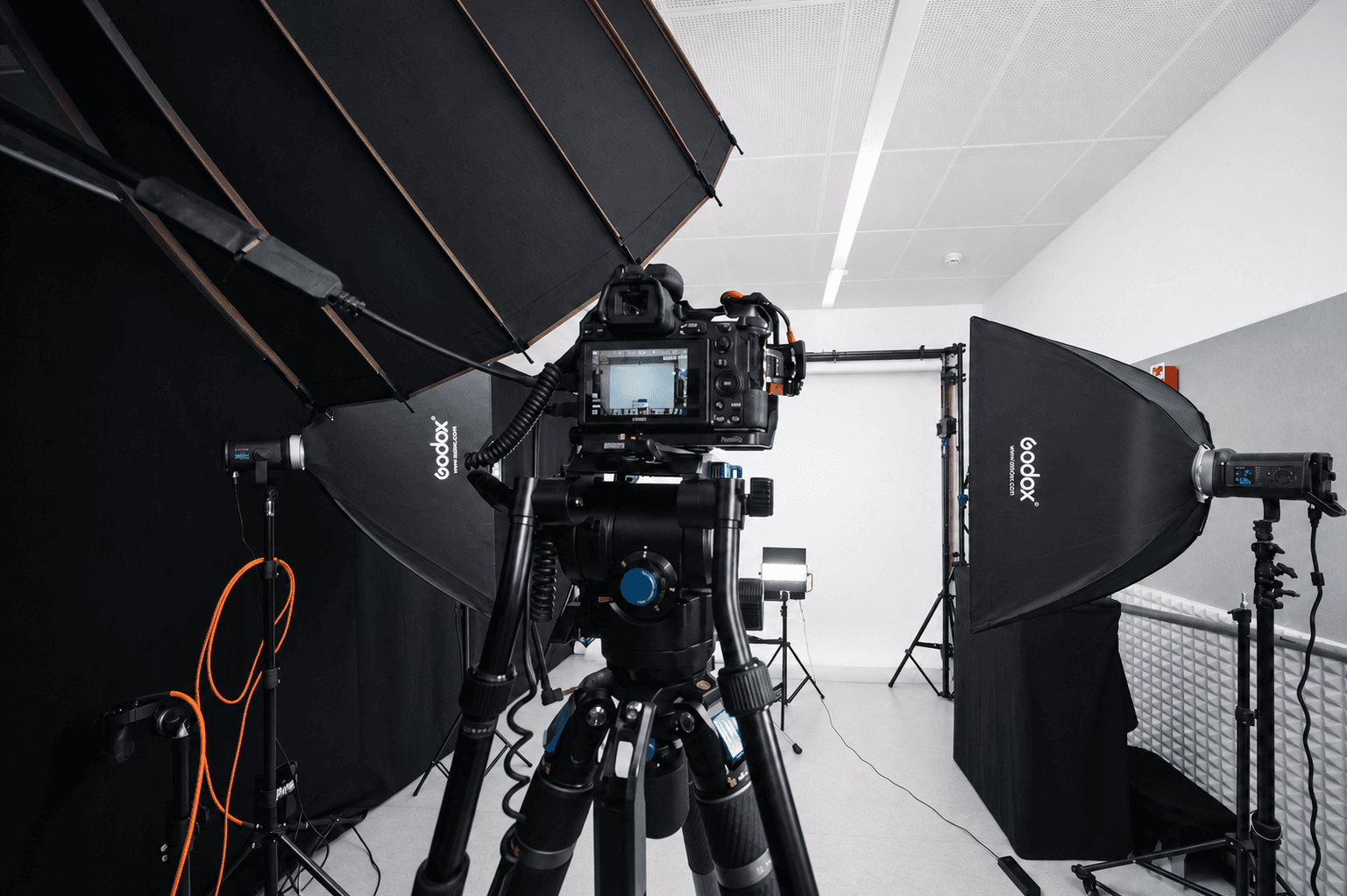 Le studio de Marly éclairé pour un tournage : caméra sur pied, boîtes à lumière et fond blanc