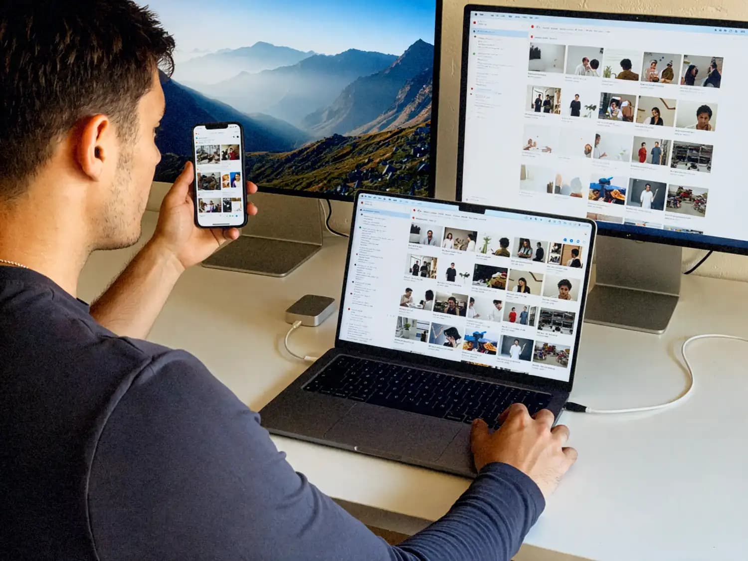 Une personne trie des photos sur son téléphone à côté de son ordinateur portable